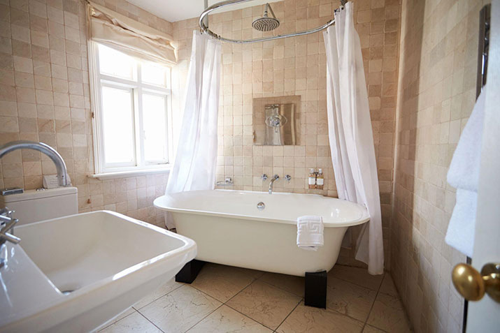 A white bathtub with a gauze shower curtain.