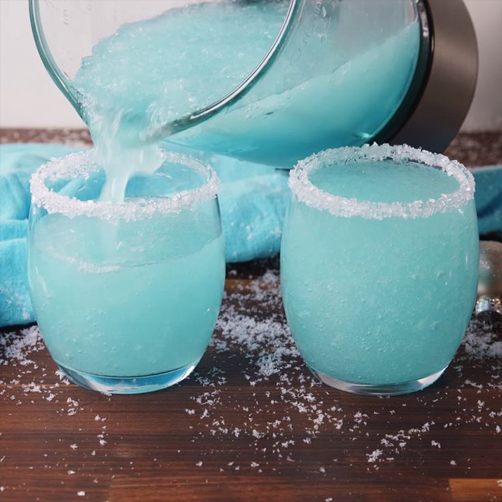 Drunk Jack Frosty - Blue frosties being poured out of a pitcher into sugar-rimmed glasses.