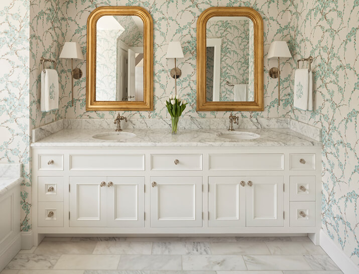 Elegant master bathroom with thick gold mirrors and white countertops.