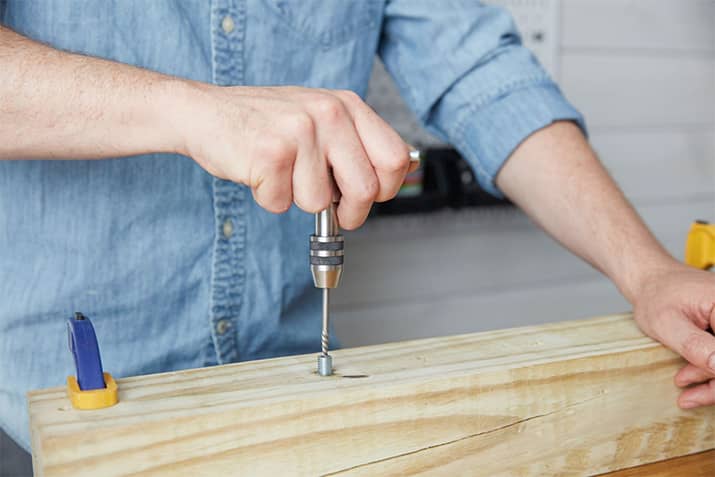 Man using screw extractor kit to remove stripped screw.