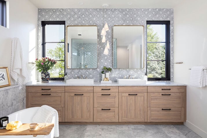 Modern master bathroom in a French modern home, with a wood vanity and marble wall tile.