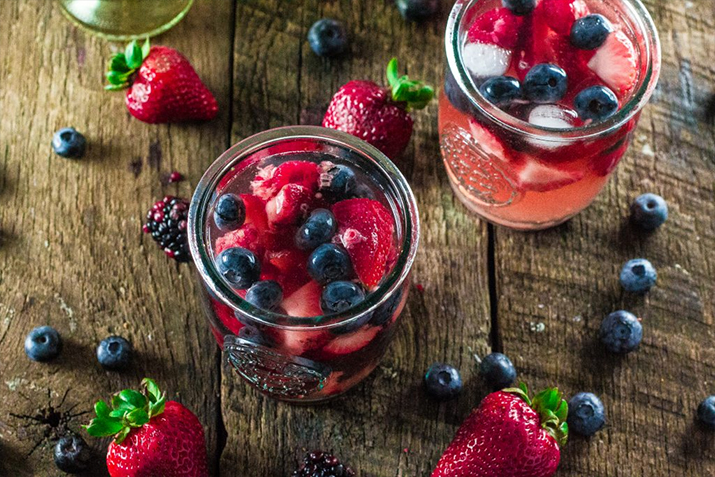 Summer Berry Sangira - Two glasses of sangria filled with strawberries and blueberries.