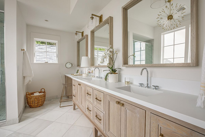 Long wood double-sink bathroom vanity with two mirrors, center drawer storage, and a seated grooming area at one end.